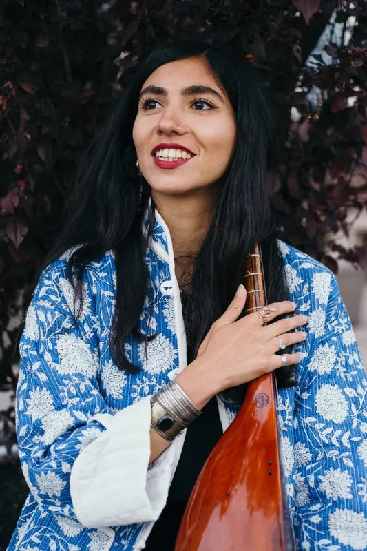 Portrait of musician and workshop facilitator Khorshid Dadbeh holding a long-necked string instrument.